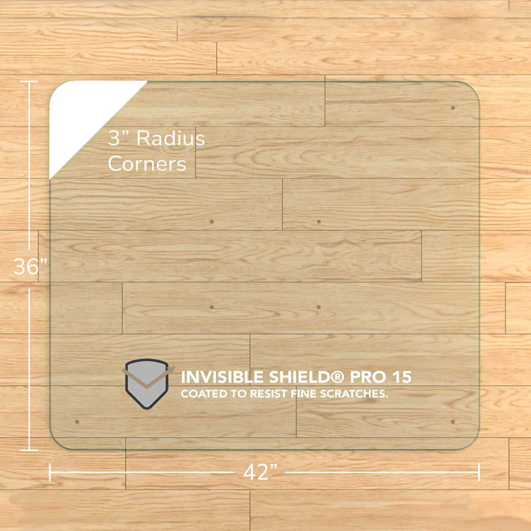 #glass clarity_chiaro (standard clear) alt="A square "chiaro" glass chair mat with dimensions of 36 inches by 42 inches, featuring 3-inch radius corners. The mat is labeled with "INVISIBLE SHIELD® PRO 15 COATED TO RESIST FINE SCRATCHES." placed on a wooden floor."