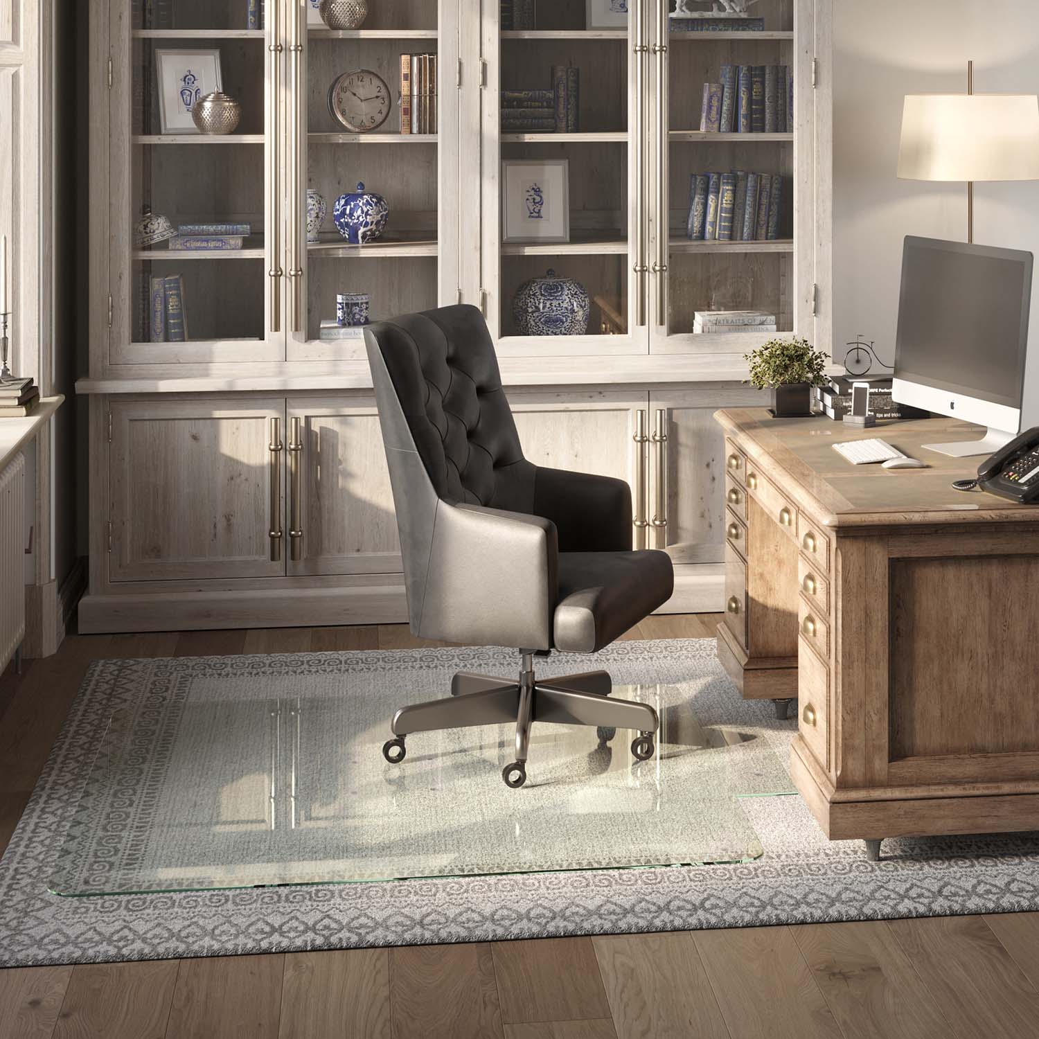 A home office with a wooden desk, computer, and black leather chair on a 60" x 60" "chiaro" tab glass chair mat over a patterned rug. Behind is a cabinet with glass doors displaying books and decor.
#Size_60x60 + Tab#Glass_Clarity_Chiaro