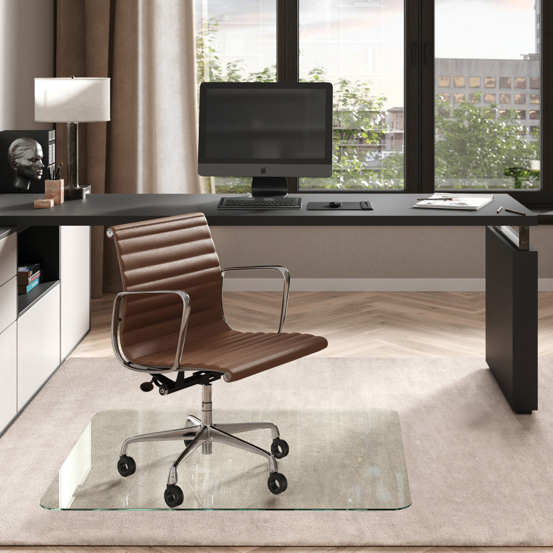 #glass clarity_chiaro (standard clear) alt="Modern home office with a black desk, computer. A brown leather chair on a 42" x 48" "chiaro" glass chair mat on a light rug."