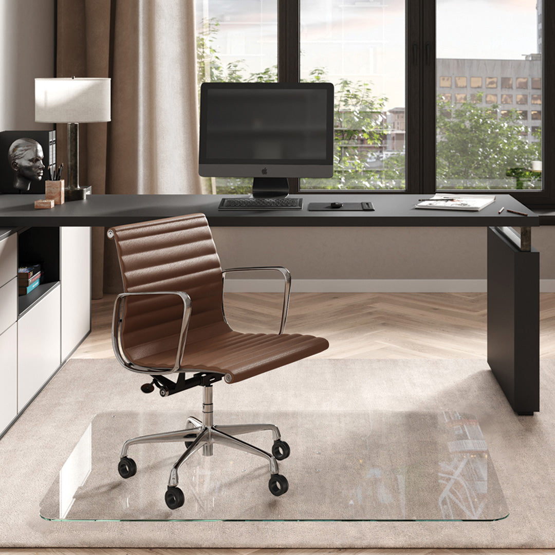 #glass clarity_luminoso (low-iron ultra clear) alt="Modern home office with a black desk, computer. A brown leather chair on a 46" x 60" "luminoso" glass chair mat on a light rug."
