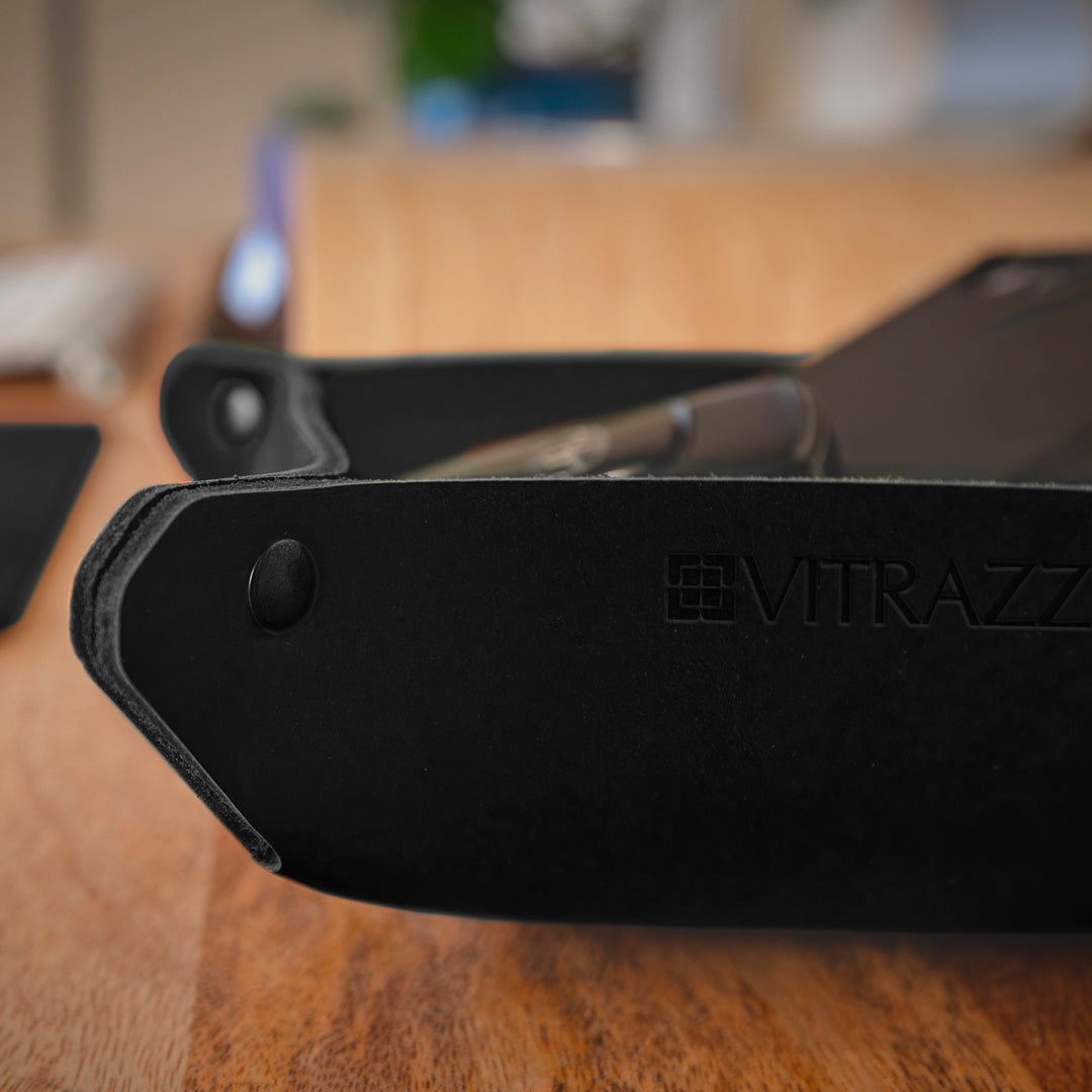#color_charcoal A close-up image of a black leather desk organizer with the brand name "VITRAZZA" embossed on it. 