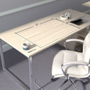 A minimalist desk setup with a light wood finish, featuring a "luminoso" glass desk mat measuring 28 inches by 18 inches. On the desk, there is a mug, a pen, a pair of headphones, and a laptop. A white office chair is positioned in front of the desk. The room has gray carpeted flooring and light gray walls with white baseboards. #Size_18x28#Glass_Clarity_Luminoso