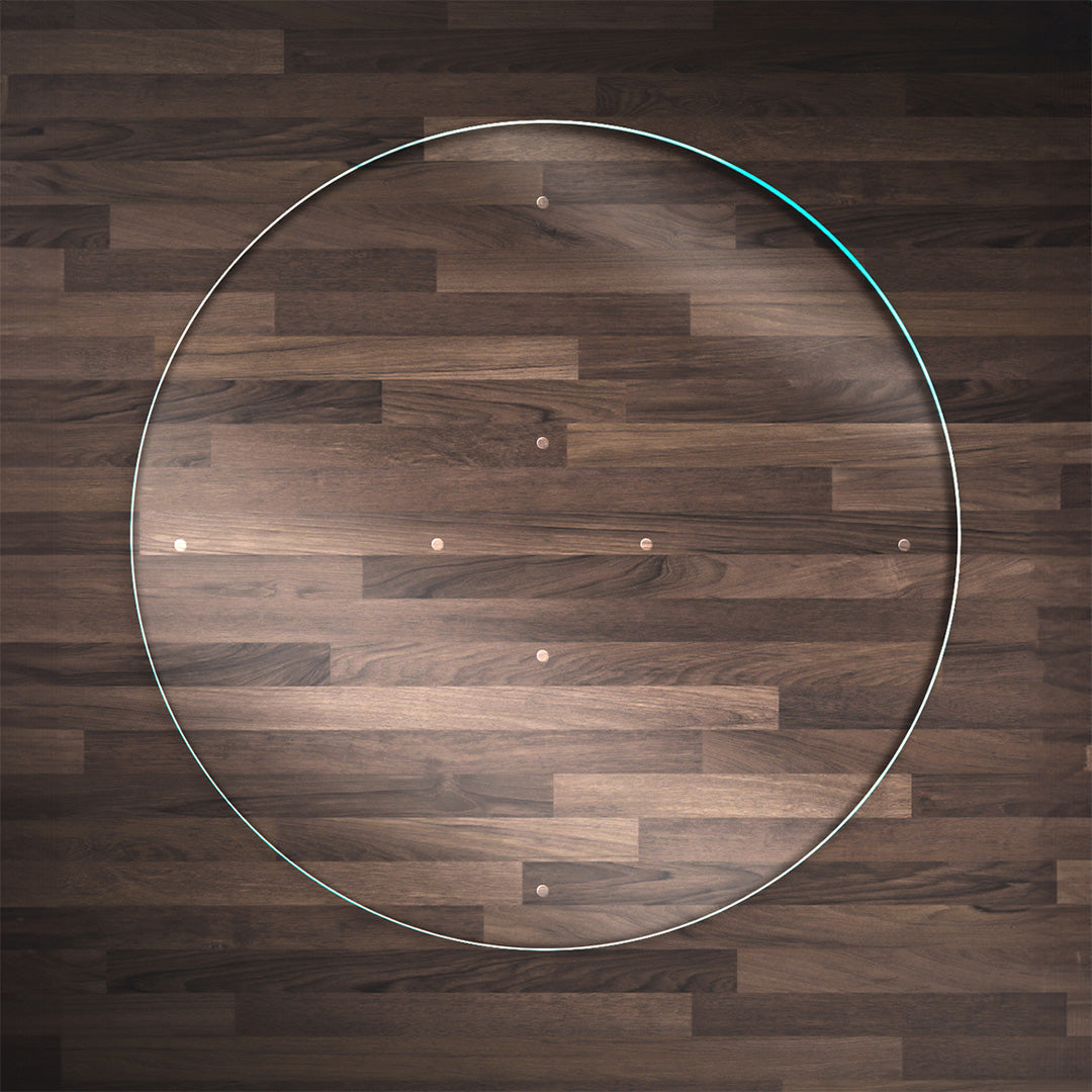 A clear Round glass chair mat, placed on a dark wood floor, and "Stabil-a-dots" for grip. The wood floor has a rich, natural grain pattern.